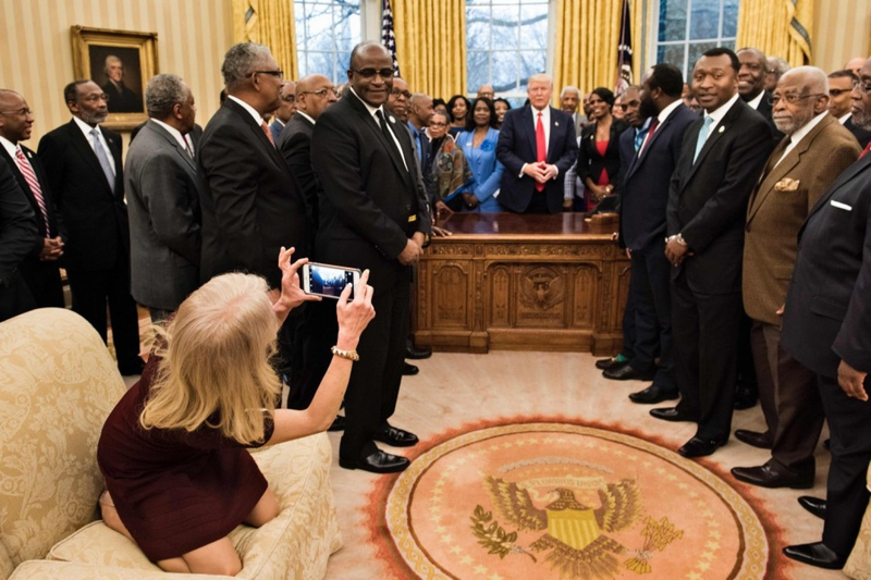 Shoes still on, Counselor to the President Kellyanne Conway takes a photo Tuesday in the Oval Office. Seeing other photos from the session, some commentators on social media thought Conway was texting. (Pool photo by Brendan Smialowski/Agence France-Presse)